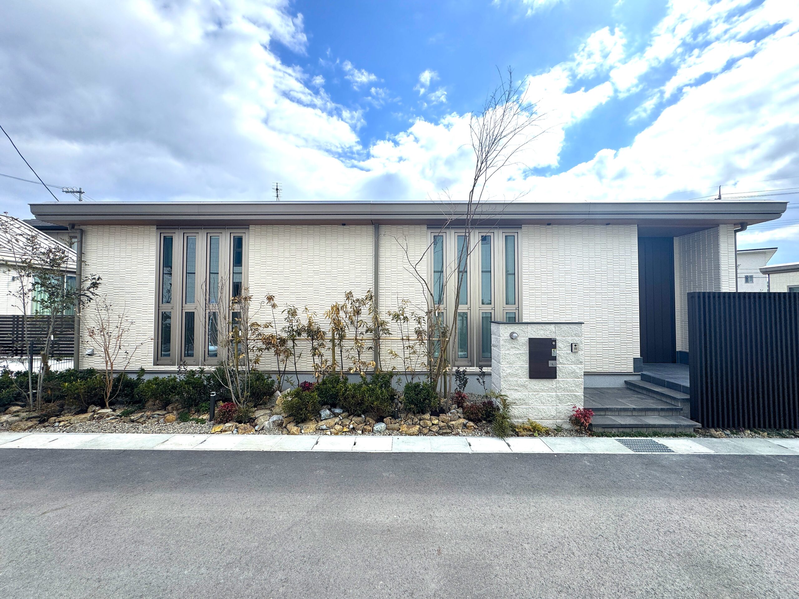 植栽が映える白い外壁で、縦のスリットが特徴の外観です。