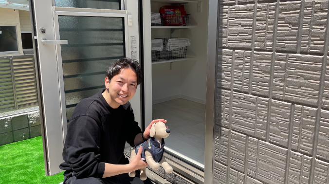 犬のぬいぐるみを手に微笑む男性の写真