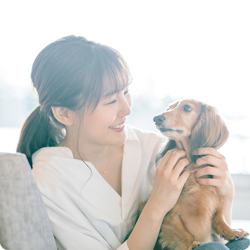 犬を両手で撫でながら笑顔の女性の写真